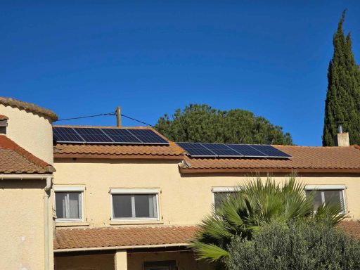 Panneaux solaires sur le toit d'un bâtiment sous un ciel bleu clair.