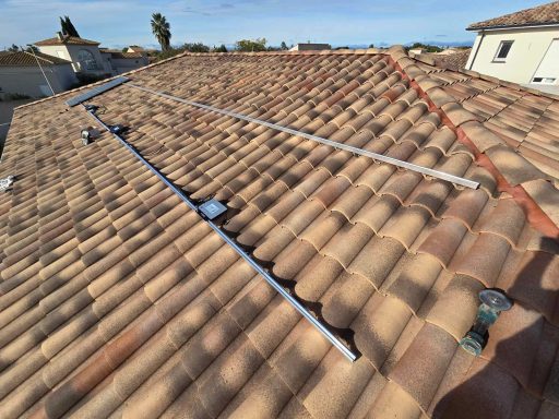 Vue d'un toit en tuiles avec des rails métalliques installés.