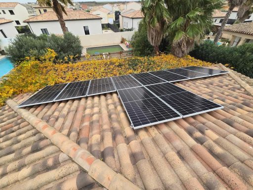 Panneaux solaires installés sur un toit, entourés de fleurs et d'une vue sur des maisons.