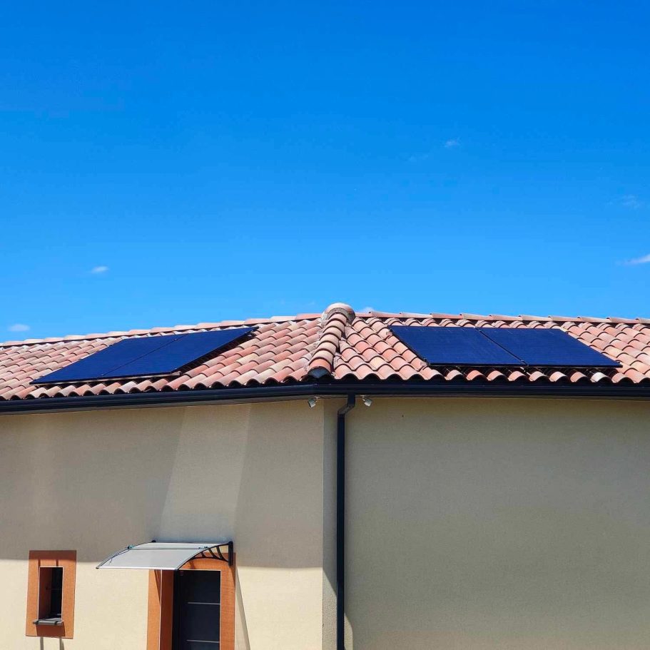 Panneaux solaires sur le toit d'une maison sous un ciel bleu.