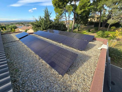 Panneaux solaires installés sur un toit, entourés d'arbres et d'un paysage résidentiel.