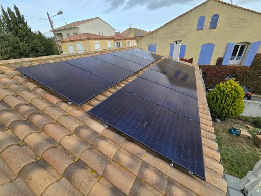 Panneaux solaires installés sur un toit en tuiles, avec une vue sur des bâtiments voisins.