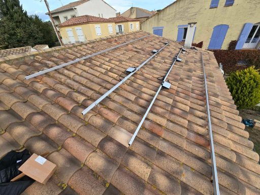 Structure métallique sur un toit en tuiles, avec plusieurs barres parallèles installées.