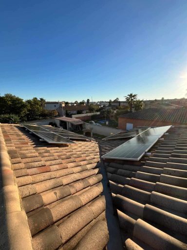 Toit avec panneaux solaires, vue sur un quartier sous un ciel dégagé.