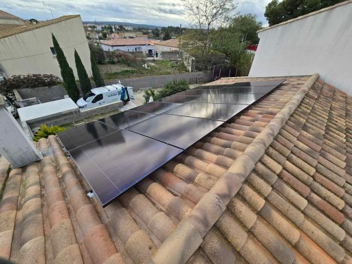 Panneaux solaires installés sur un toit en tuiles avec un paysage urbain en arrière-plan.